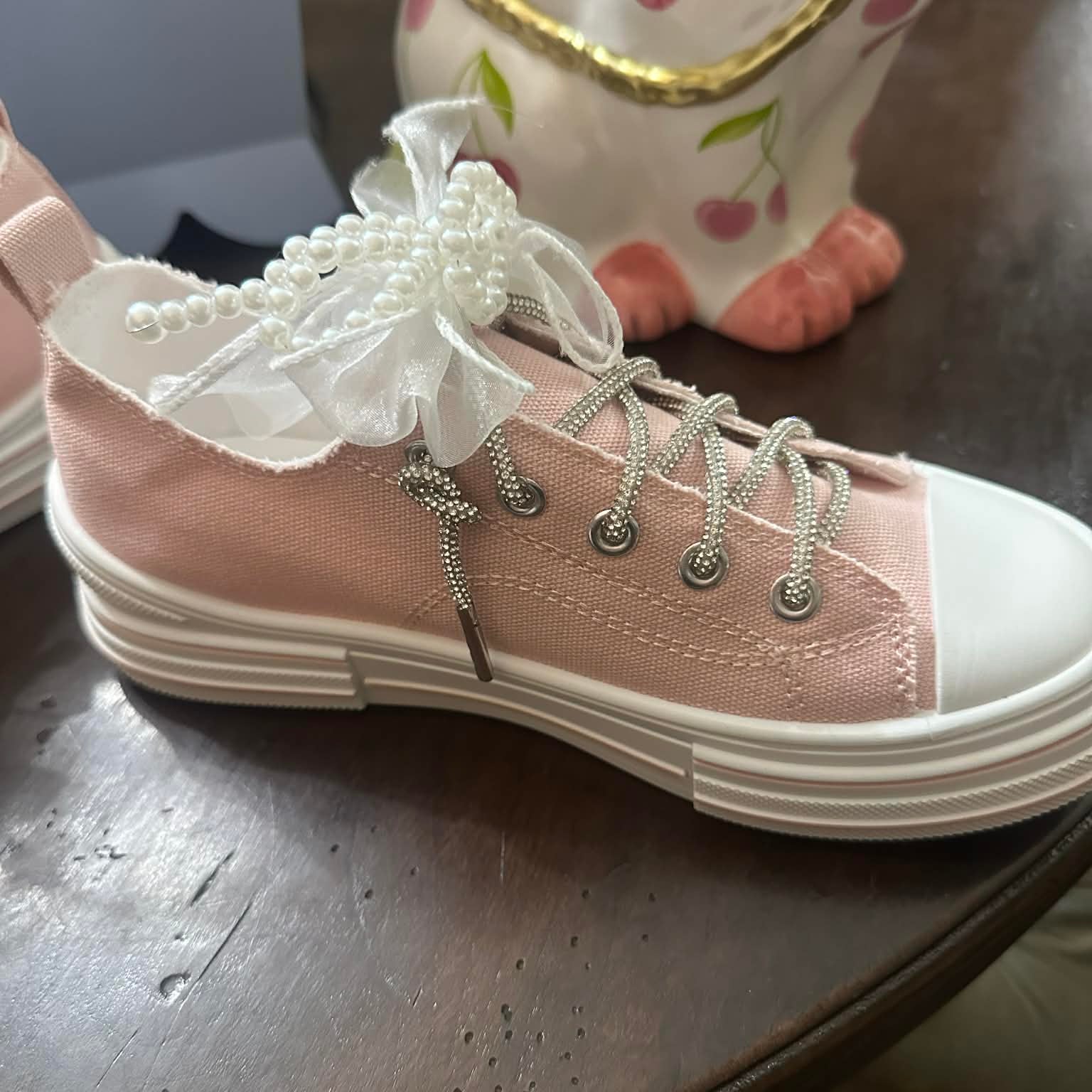 Pink sneakers with white laces on a wooden surface