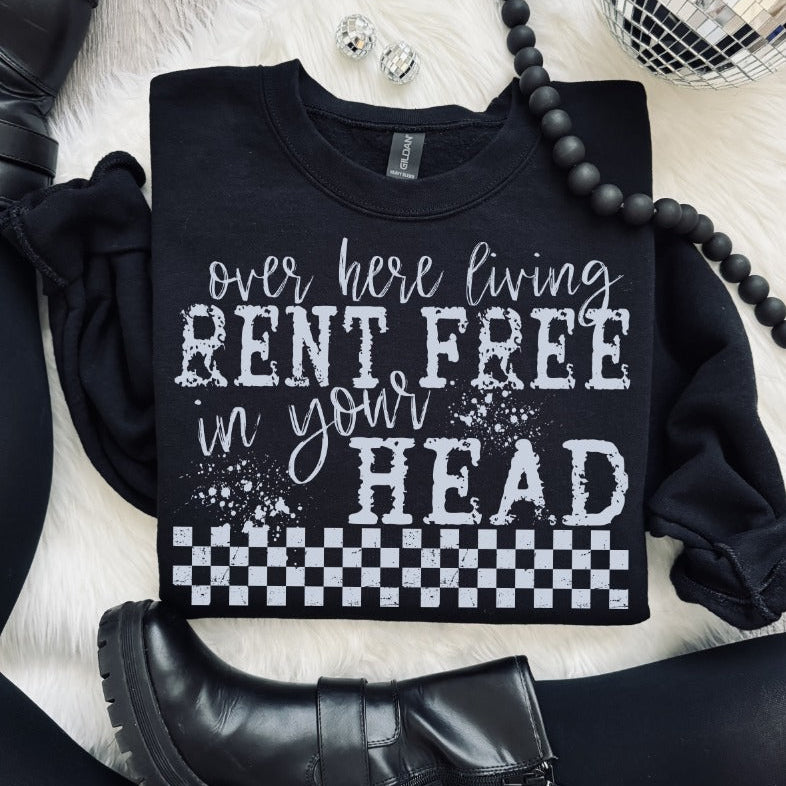 Black sweatshirt with white text on a white surface with black shoes and jewelry.